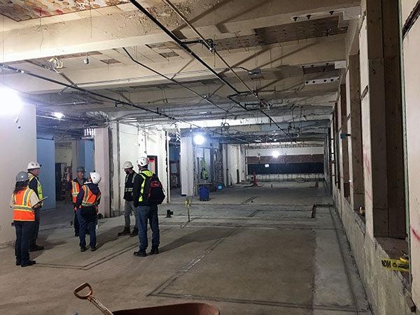 workers standing in a large open area in a building under construction