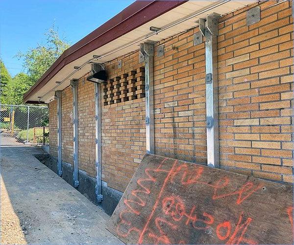 a brick building has steel beams installed vertically on it