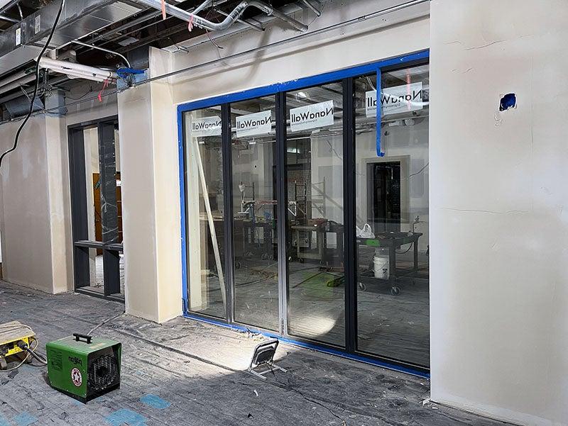 an unfinished gypsum covered wall has a four-panel glass door installed