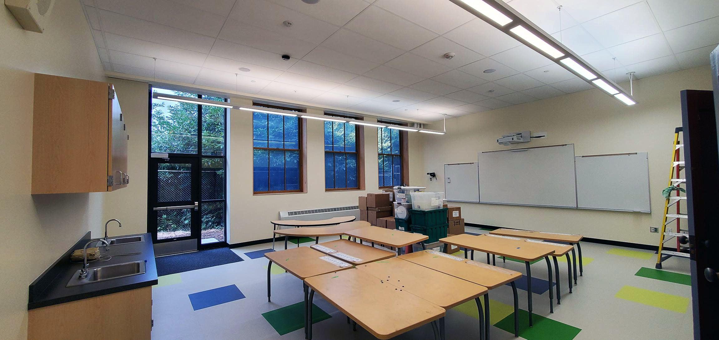 a classroom with a door leading outside and windows on one wall