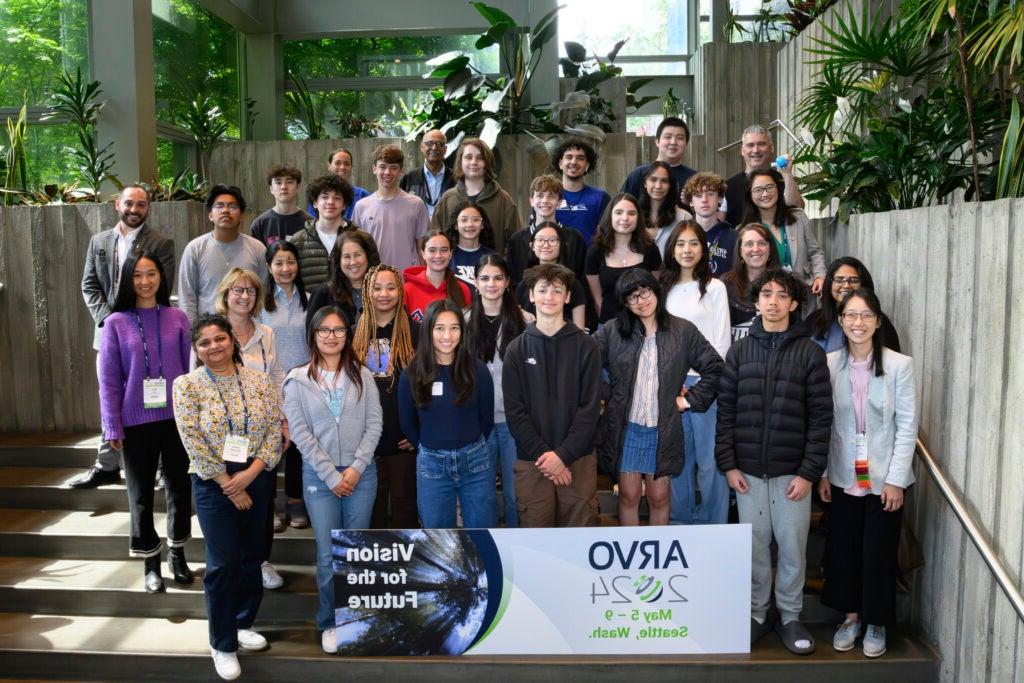 Group of students posing in front of ARVO conference poster