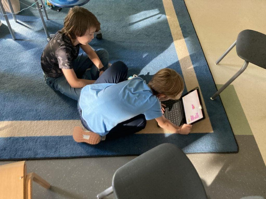 Students sitting on carpet and coding together for FLL team